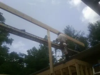 Carpenter setting a ridge beam over a new addition frame — Ice Dam Removal by Roofing Brothers in Taylor